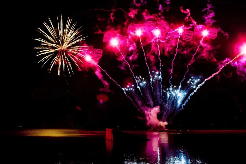 LEGOLAND Florida Red fireworks bursting over lake at night with red LEGO blocks in the sky. There is also a huge gold firework in the sky.