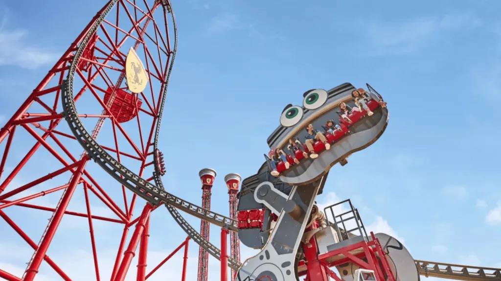 Crazy Pistons und Red Force in Ferrari Land Personen auf einem Fahrgeschäft mit einer riesigen Achterbahn im Hintergrund