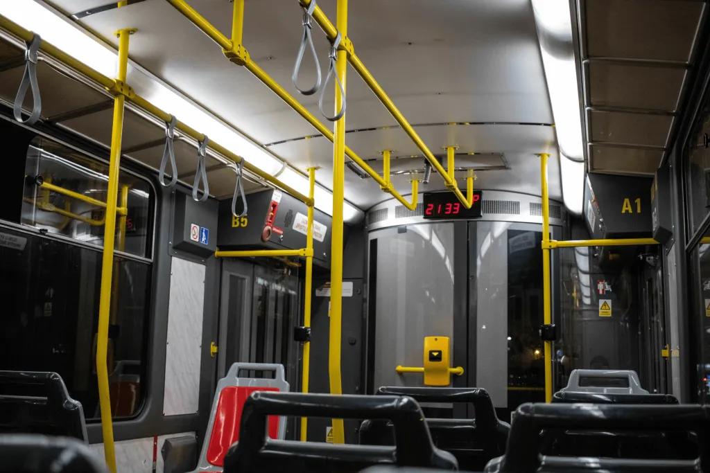 Public Transport There is a grey bus with yellow poles to hold on to.