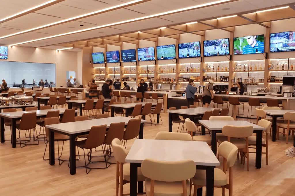 Crush Yard Pickleball Club & Restaurant Cream coloured restaurant with bars lining the wall and multiple flat screen tvs.
