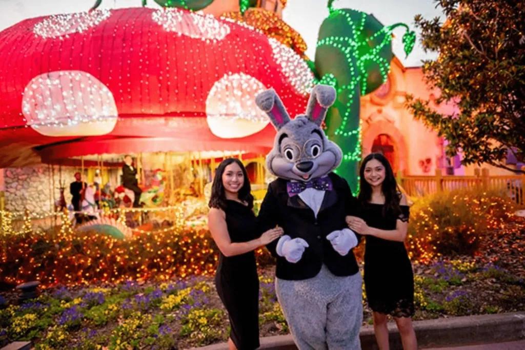 Enchanted Carousel A bunny dressed in suit stood with two young girls in front of a giant toad stall with a carousel underneath.