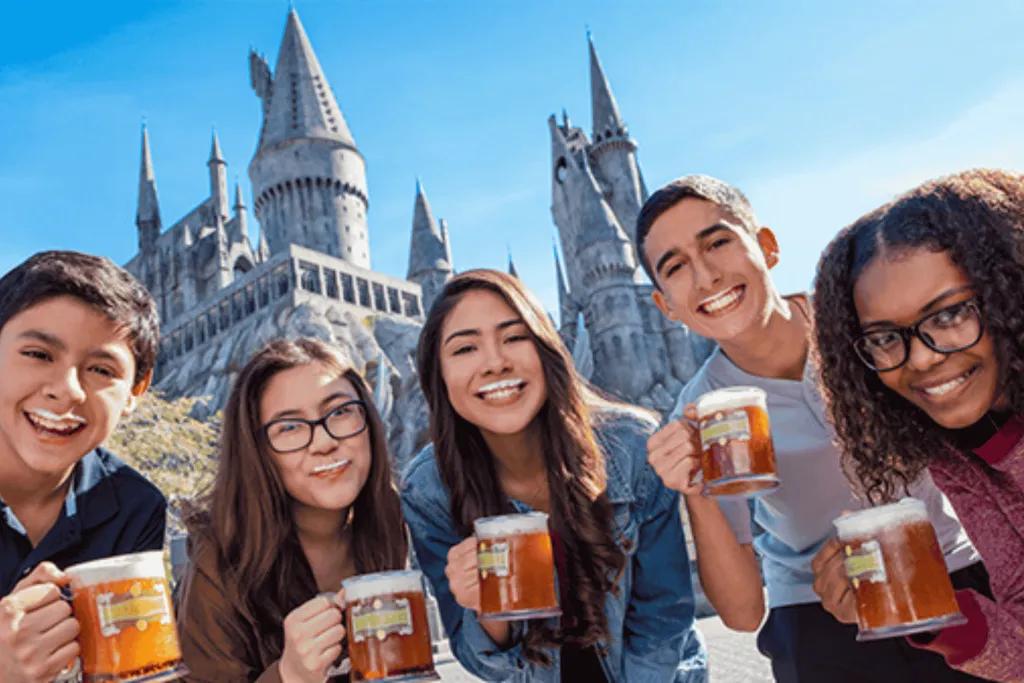 Butterbeer Season A group of young adults posing with mug of Butterbeer in front of Hogwarts castle