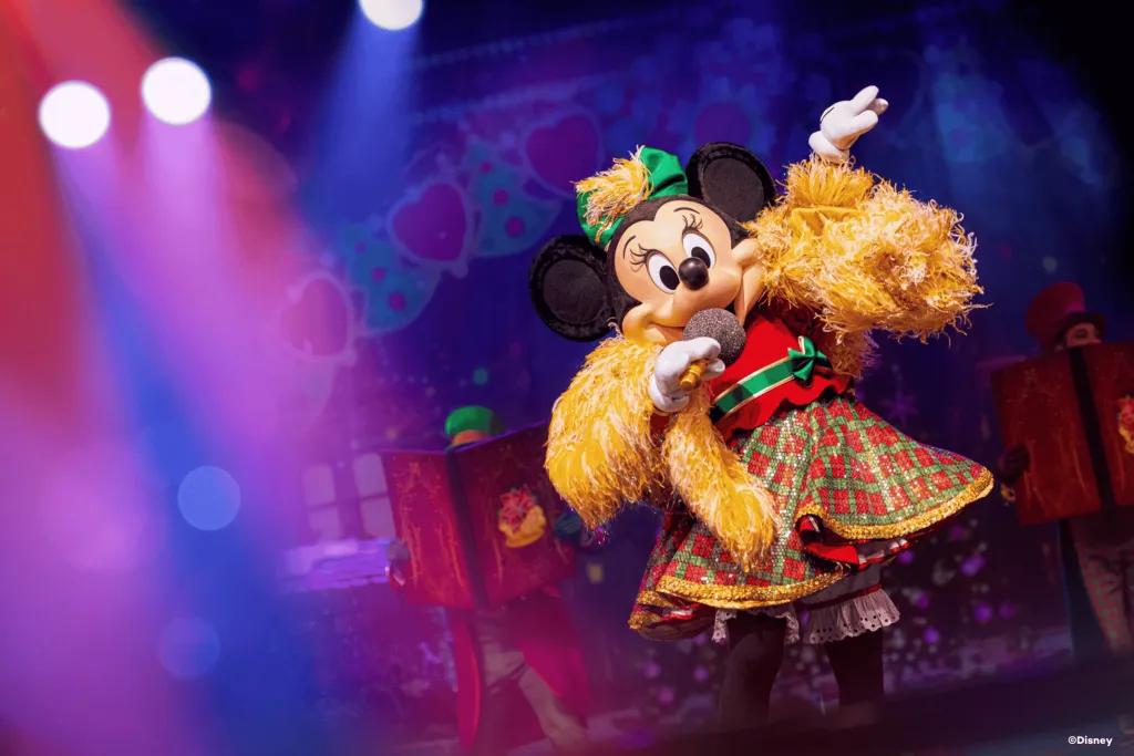 Let's Sing Christmas Minnie Mouse wearing a Christmas outfit and singing into a mic onstage