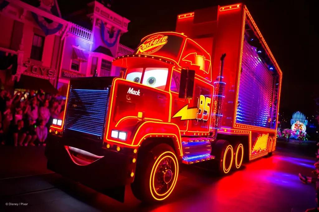 Hook in der Paint the Night Parade Hook aus Cars, ein riesiger roter Truck mit einem grinsenden Gesicht auf der Vorderseite, leuchtet in rotem Neonlicht. Er ist mit gelben Blitzen geschmückt.