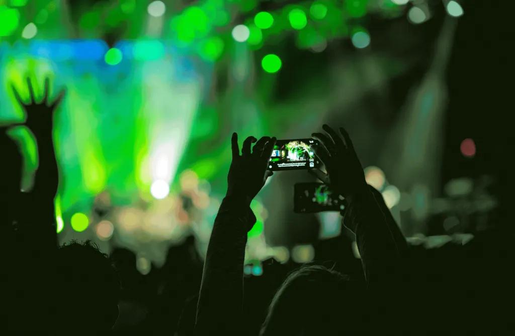 Mardi Gras Concerts Someone in a crowd at a concert holding their phone above their head to take a picture of the stage
