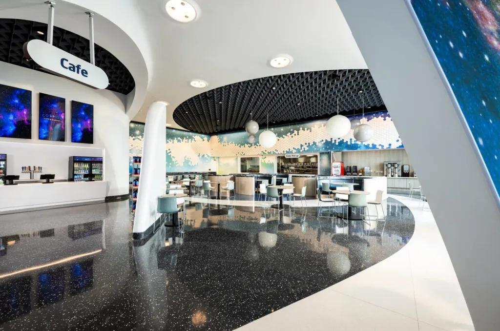Cosmos Cafe at Universal Stella Nova Resort An empty cage with curved walls and counters and spacious chairs and tables