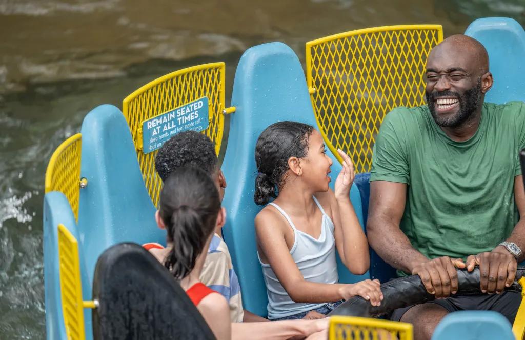Infinity Falls A family smiling while getting splashed on a raft ride