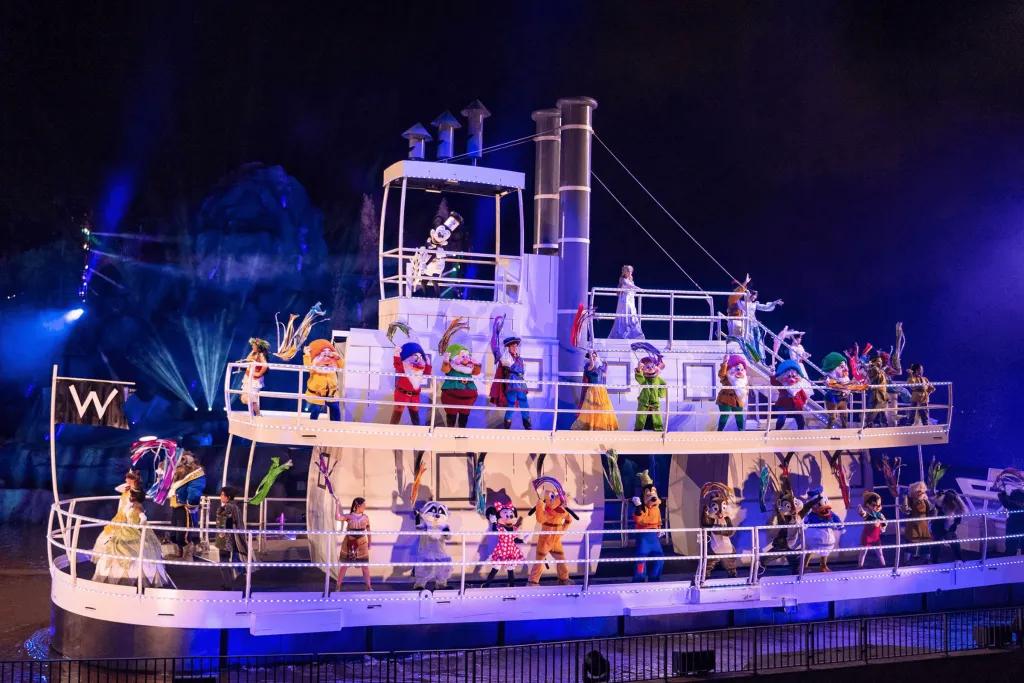 Fantasmic! An old white steamboat full of almost all of the Disney characters, including all princesses, cartoon characters and Mickey driving the boat over a lake. They are all waving a colourful prop.