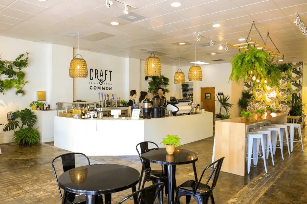 Craft and Common Open air, light white coffee shop decorated with plants.