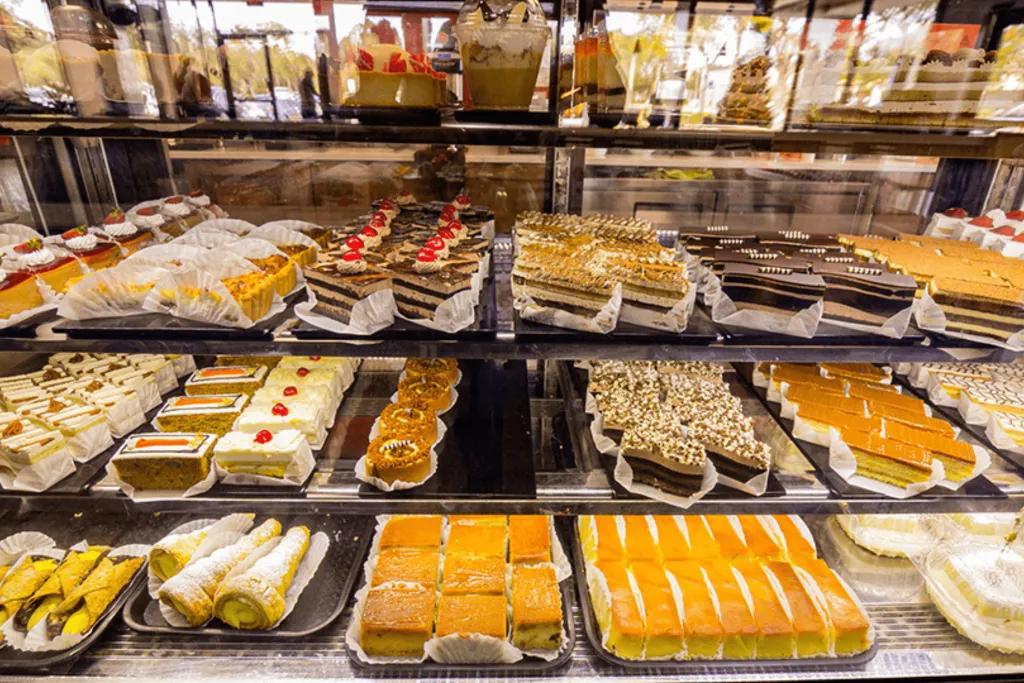 Mecatos Bakery & Cafe A selection of different pastries and cakes behind a glass case in a cafe.