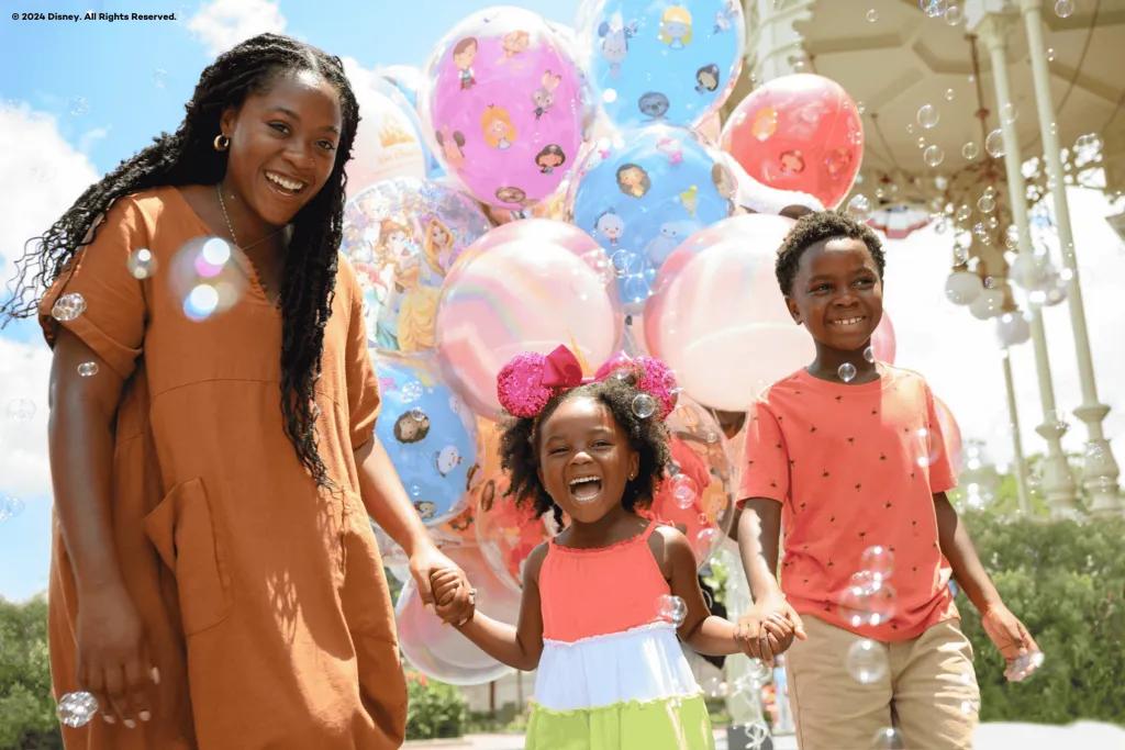 Walt Disney World Resort A mum with her young son and daughter in front of Disney themed balloons