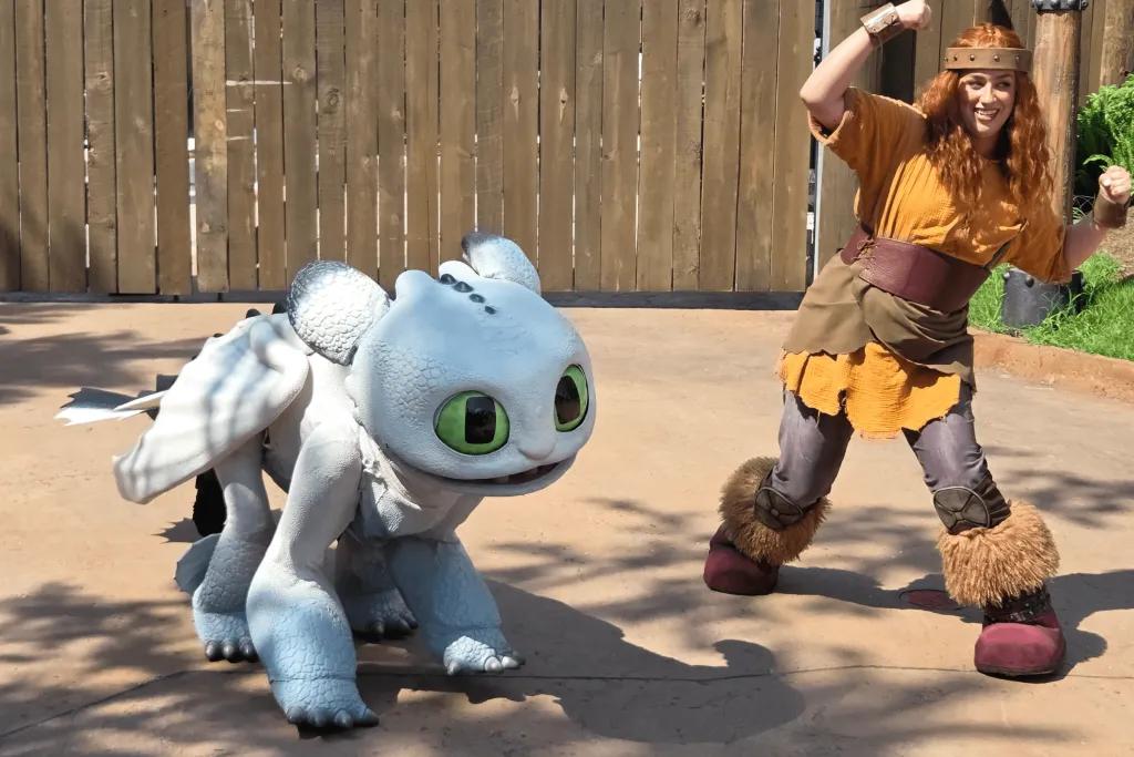 Isle of Berk Baby white dragon stood with its viking trainer.