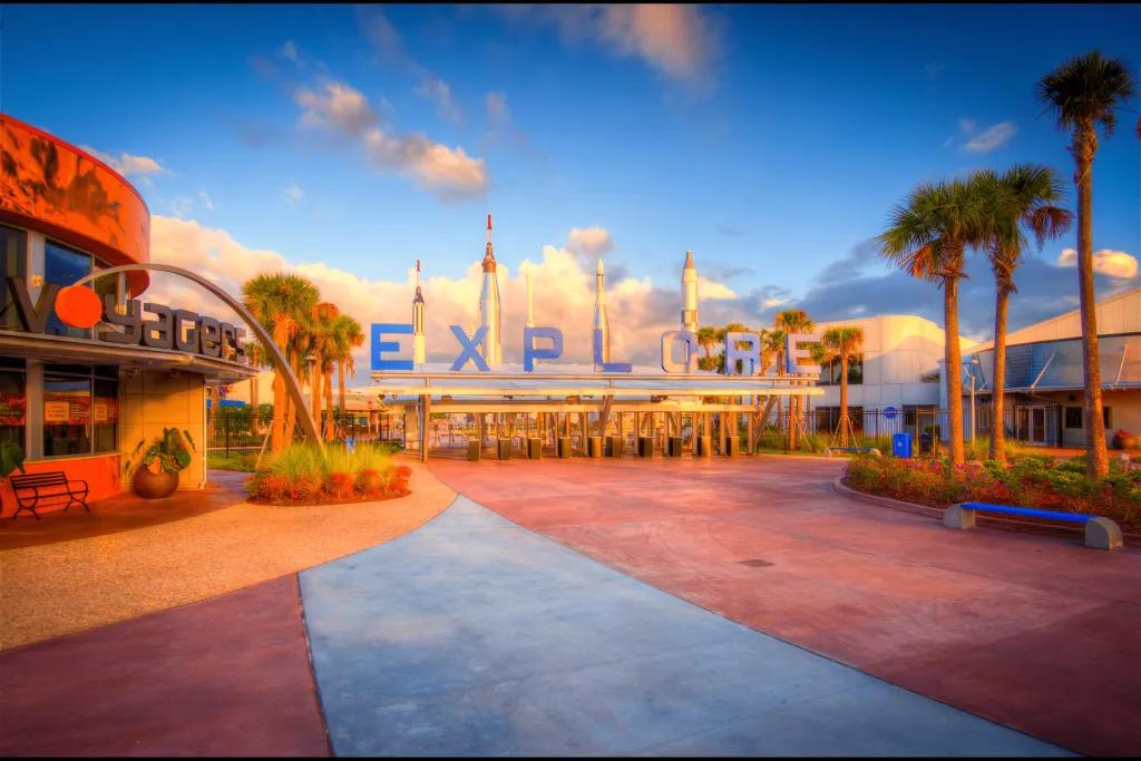 Kennedy Space Center Rocket garden behind a large sign saying "EXPLORE".
