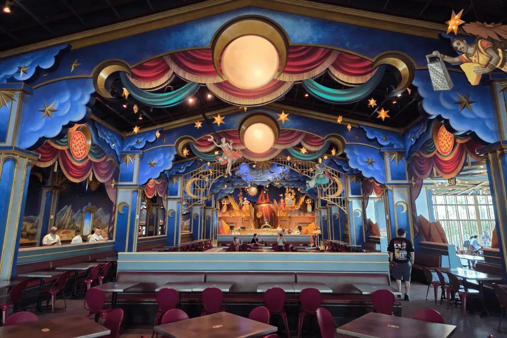 Pizza Moon Grand hall with red table and chairs for dining and behind there's a bar and extravagant decorations, featuring stars, planets and more space theming!