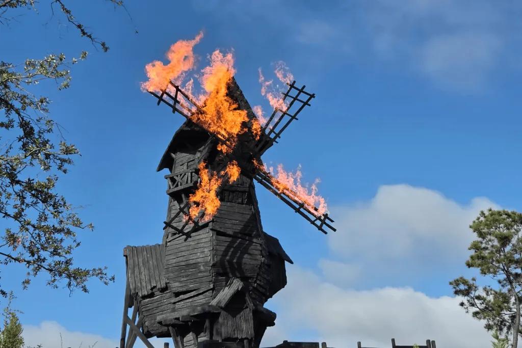 Dark Universe A wooden windmill spinning around with each of its four arms set on fire