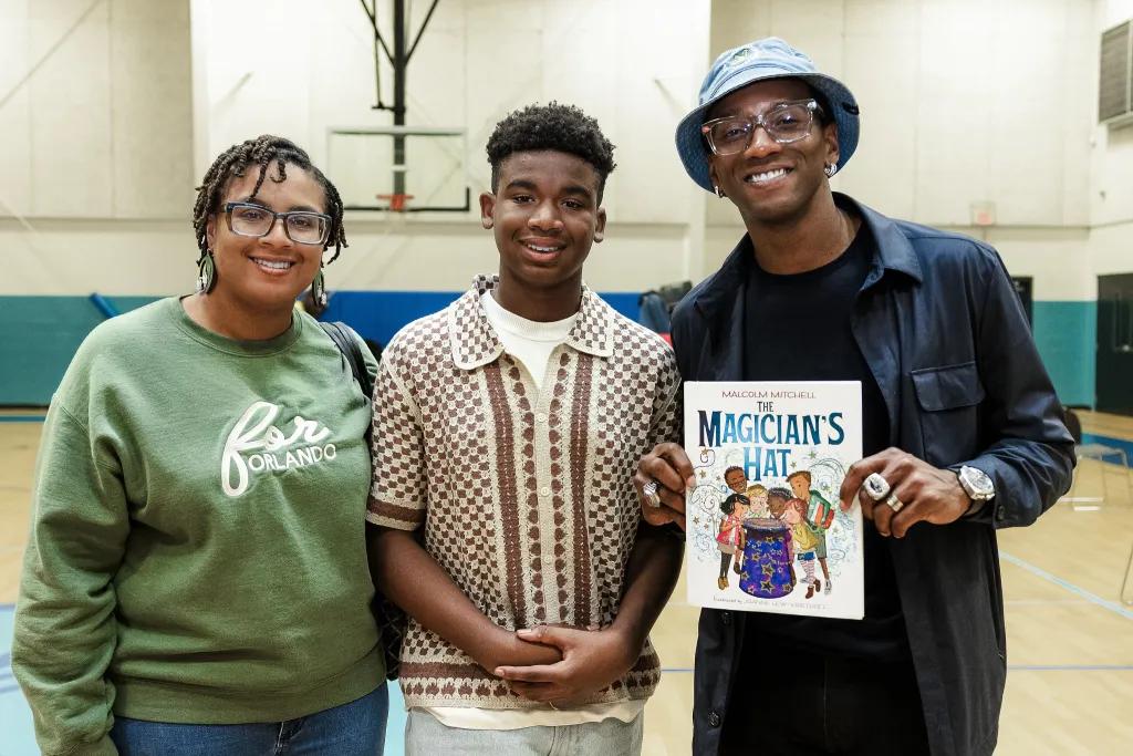 Reed Charitable Foundation Three people smiling at the camera, one holding a children's book