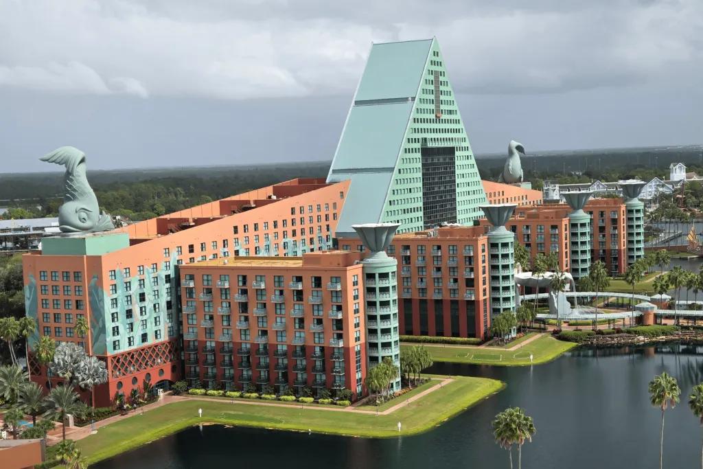 Large coral and turquoise hotel with stone fish statues on top. There's a large lake in front of it.