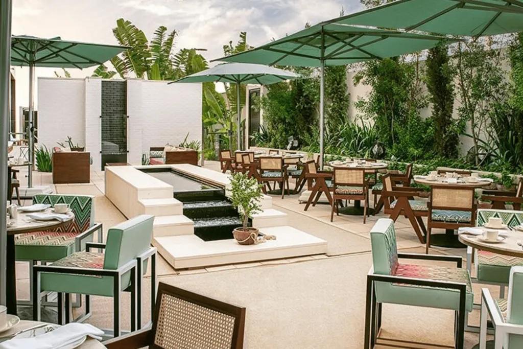 Terrace with dining tables and chairs under umbrellas outdoors.