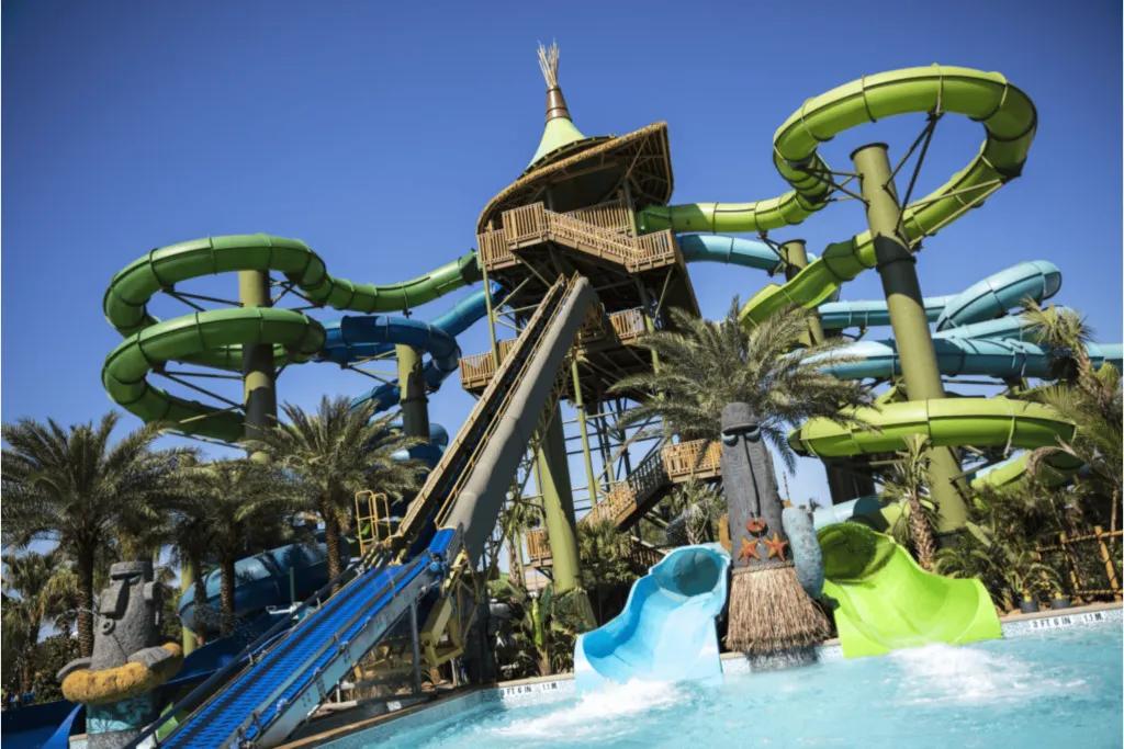 A wide shot of multiple brightly coloured water slides twisting around a central themed structure, showcasing the exciting attractions available at Universal's Volcano Bay within Universal Orlando Resort.