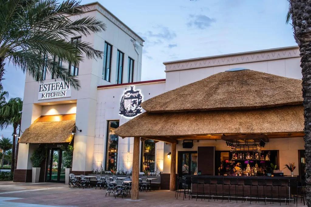 White restaurant called Estefan Kitchen, and has a thatch roof bar outside.