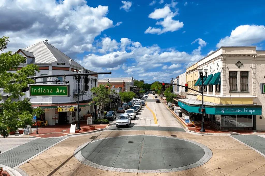 Cute American town like a movie with a roundabout and cars lining one side of the street.