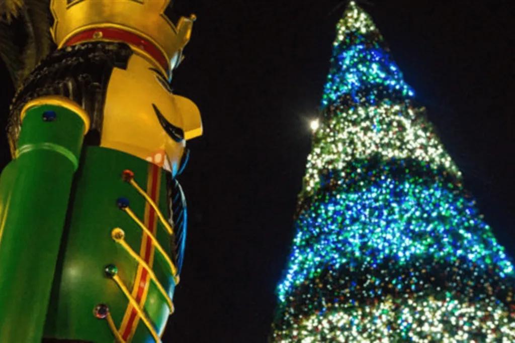 Giant green nutcracker in front of a large Christmas tree