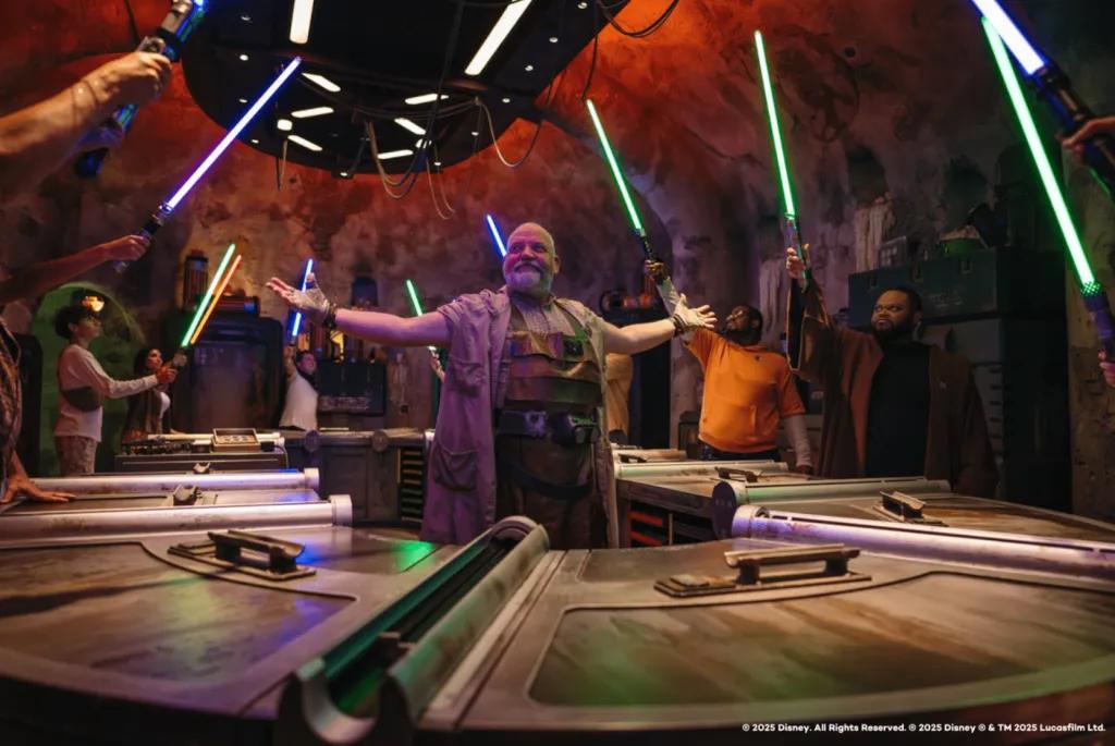 A group of guests raising their custom-built, glowing lightsabers during a building ceremony at Savi’s Workshop in Star Wars: Galaxy’s Edge.