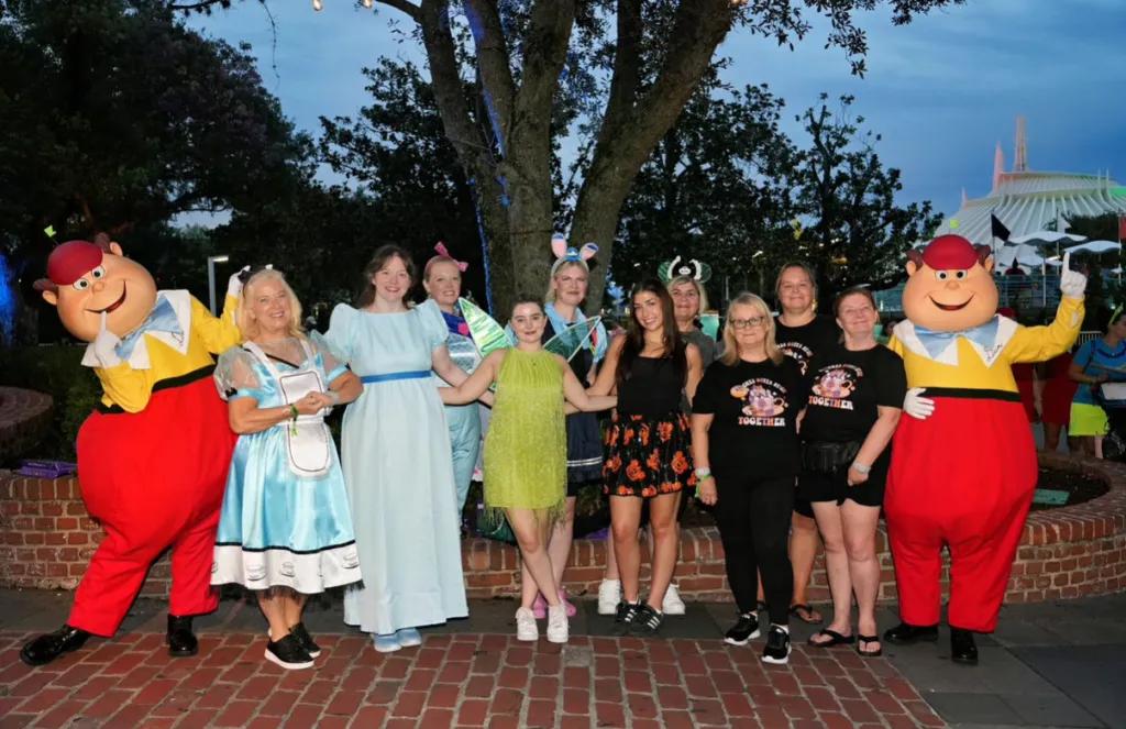 A group of AttractionTickets.com employees in character costumes posing at dusk in Disney World during a team FAM trip.