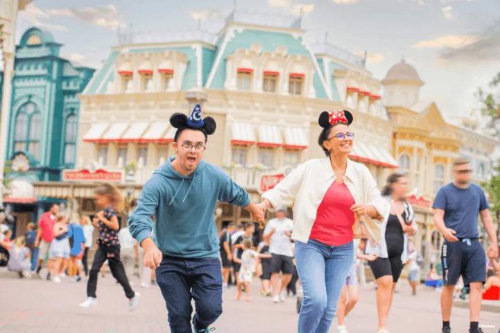 A man and woman running joyfully at a theme park