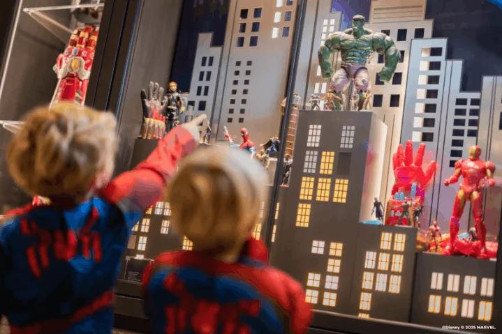 Two children pointing at figurines inside Disney's MARVEL-themed hotel