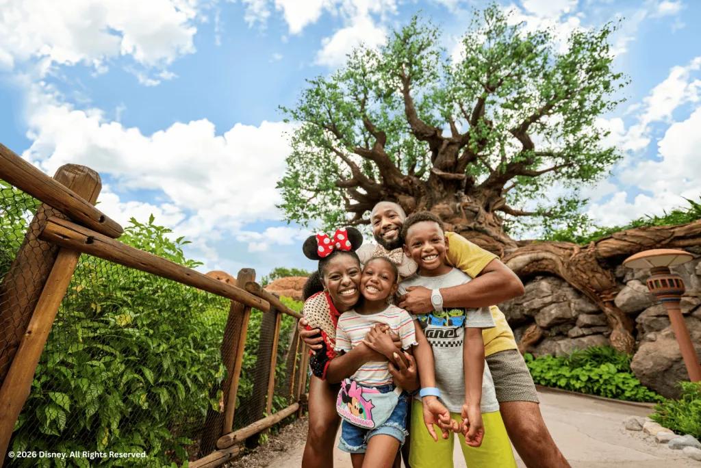 Family posing and smiling in front of the Tree of Life at Disney's Animal Kingdom