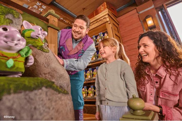 Family interacting with a cast member and Trolls figures inside Fjord View Shop, World of Frozen