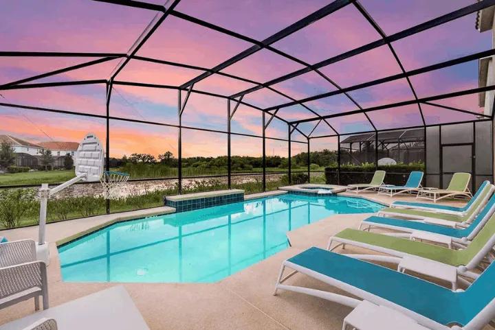 Screened private pool with lounge chairs at an Orlando villa during sunset