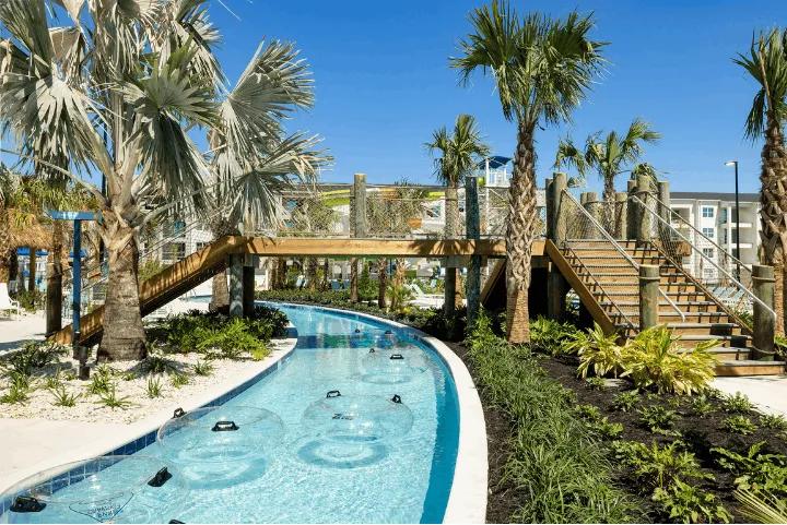 Lazy river winding through palm trees with a wooden bridge at Villatel Orlando Resort