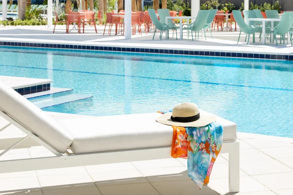 A sun lounger with a sun hat and scarf by the pool at Villatel Orlando Resort