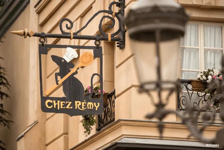 A wrought-iron sign featuring Rémy holding a wooden spoon hanging outside Bistrot Chez Rémy at Disney Adventure World