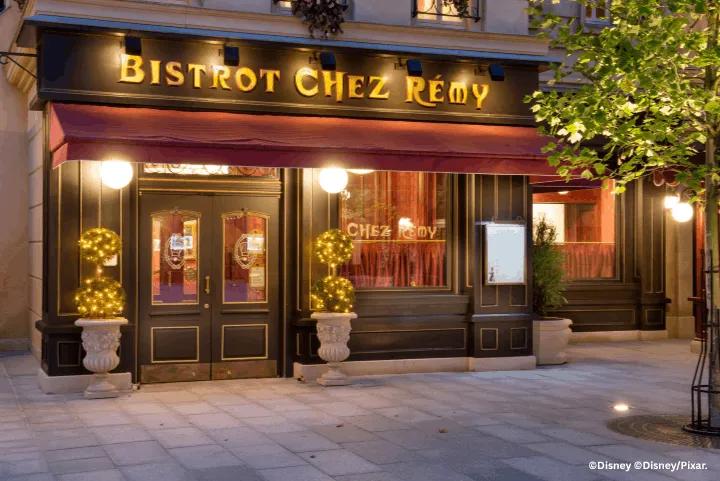 The illuminated entrance and storefront of Bistrot Chez Rémy at Disneyland Paris during twilight
