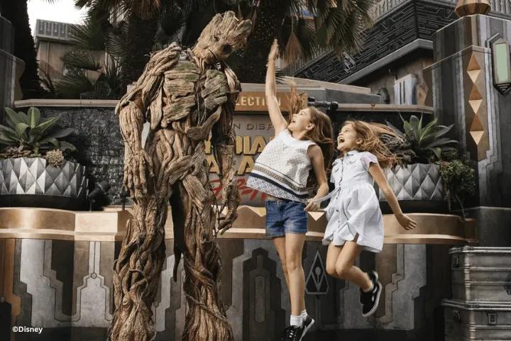 Two young girls jumping in excitement while posing next to Groot outside Guardians of the Galaxy – Mission: BREAKOUT!