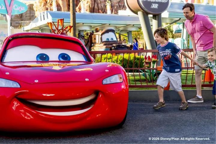 A excited young boy running up to Lightning McQueen in Cars Land with Tow Mater parked in the background