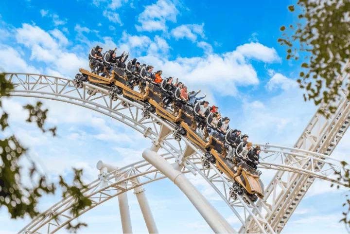 Riders cresting the top of a hill on Hyperia roller coaster against a blue sky at Thorpe Park