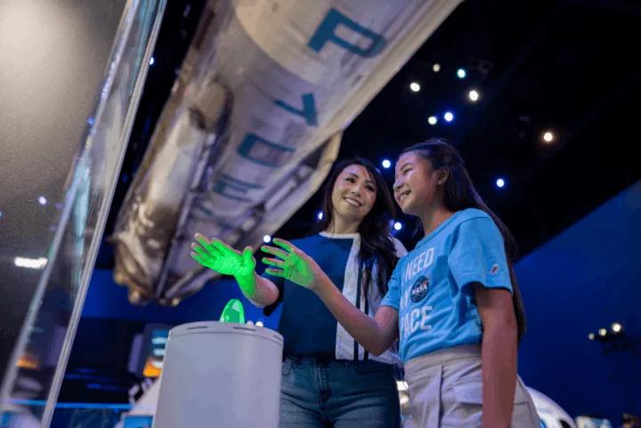A mother and daughter interacting with a green light display in Gateway exhibit hall