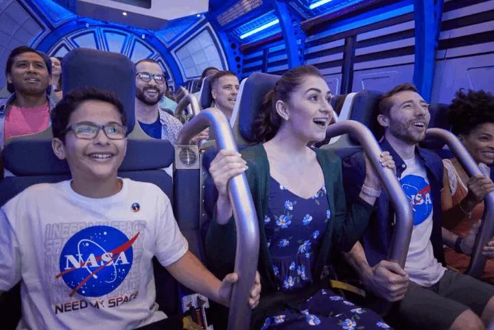 Guests wearing NASA shirts smiling inside the Shuttle Launch Experience simulator