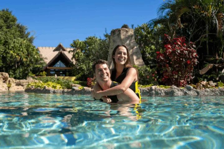 A smiling couple floating together in the clear tropical waters of the Wind-Away River at Discovery Cove in Orlando, Florida
