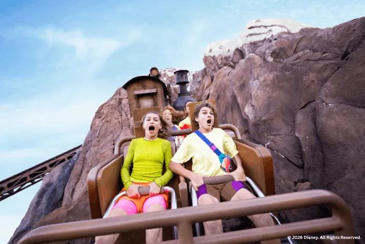 Thrilled riders cheering on the Expedition Everest roller coaster train as it climbs the steep mountain peak