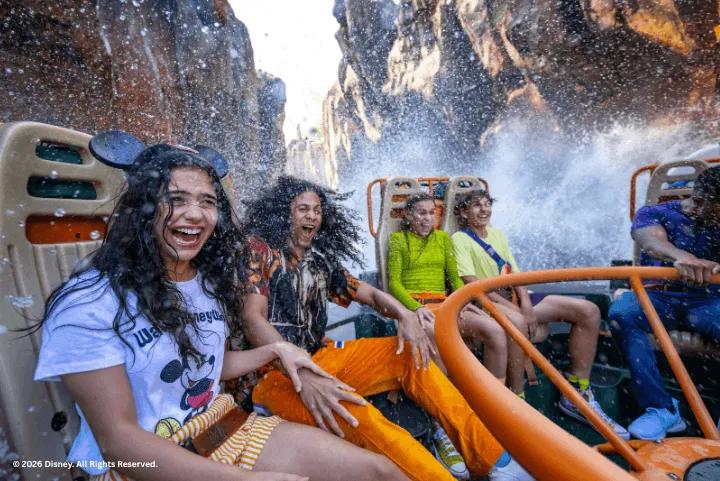 Excited guests laughing as water splashes over their raft on Kali River Rapids