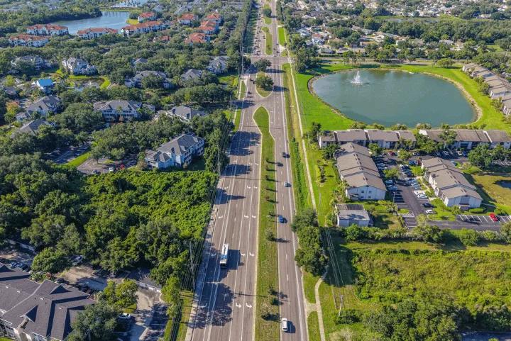 Aerial view of a multi-lane highway running through a suburban neighborhood with a small lake