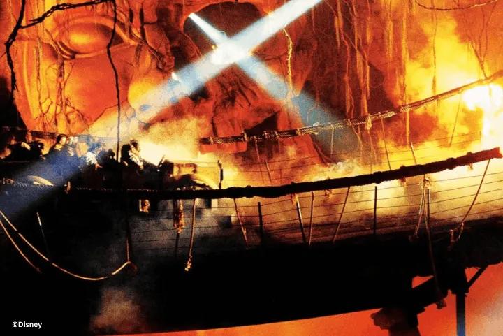 A ride vehicle crossing the suspension bridge inside Indiana Jones Adventure: Temple of the Forbidden Eye, illuminated by blue spotlights amidst fiery caustics