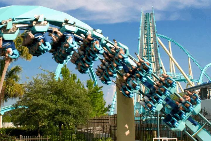 Kraken floorless roller coaster riders upside down on a teal loop with the lift hill in the background at SeaWorld Orlando