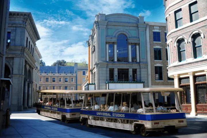 Studio tour trams passing New York Street backlot buildings at Universal Studios Hollywood