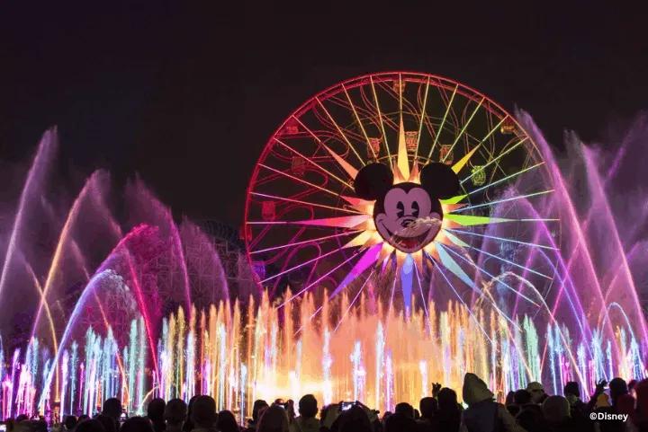 Colorful illuminated water fountains shooting into the night sky in front of Pixar Pal-A-Round during the World of Color nighttime spectacular